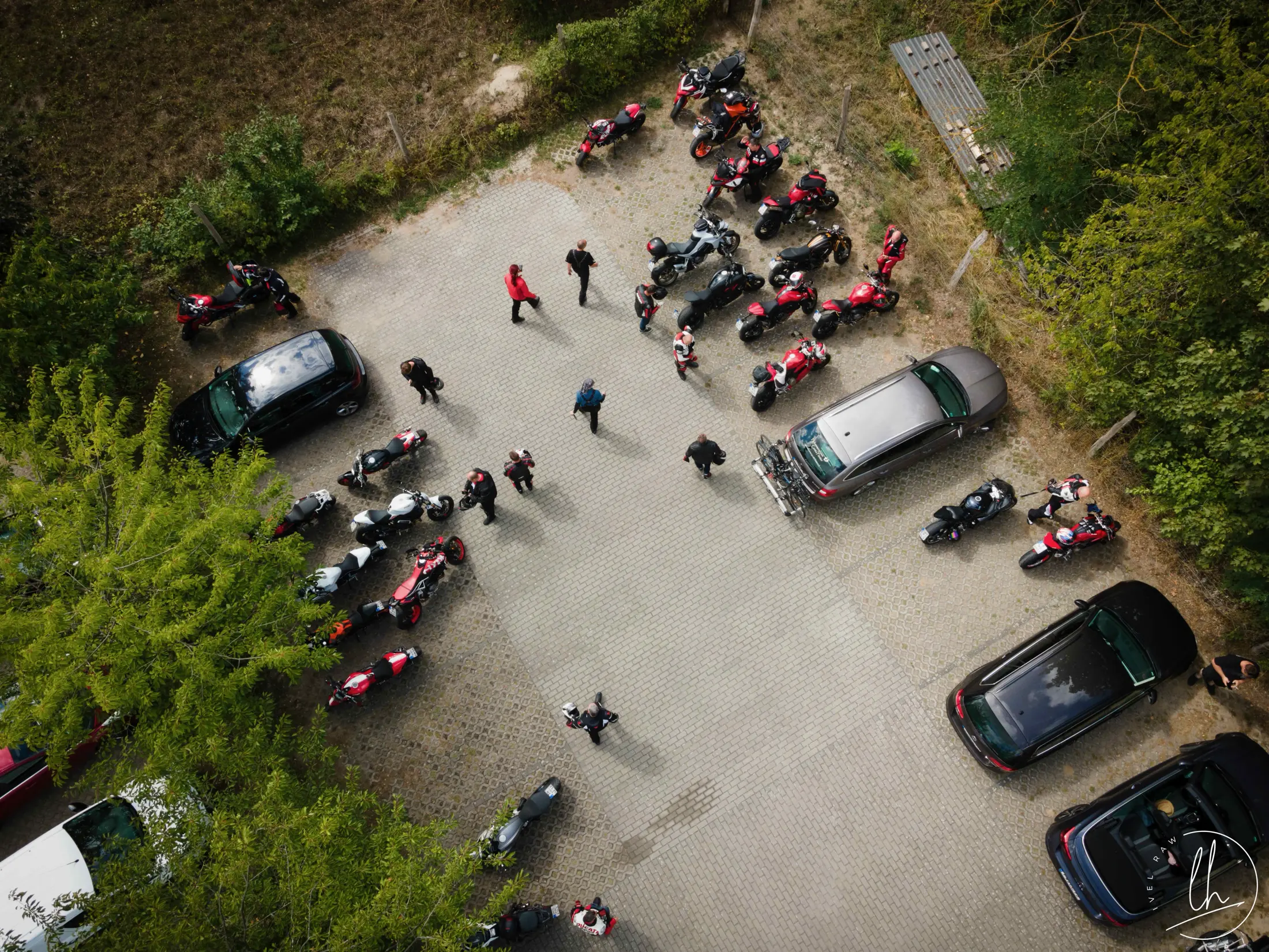 Luftaufnahme eines Clubtreffens: viele Ducatis auf einem Parkplatz im Grünen