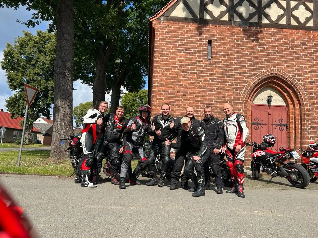 Gruppenfoto mit Ducatis vor einer Backsteinkirche